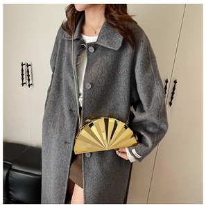 Detail of elegant gold shell evening clutch bag with metallic pleated fan texture on model
