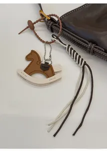 Close-up of brown and beige leather rocking horse bag charm with detailed stitching