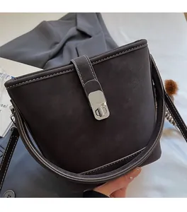 Gros plan d'un sac seau en cuir marron avec fermoir rotatif argenté et surpiqûres blanches