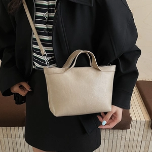 Detailed view of beige PU leather tote bag with silver hardware on black outfit