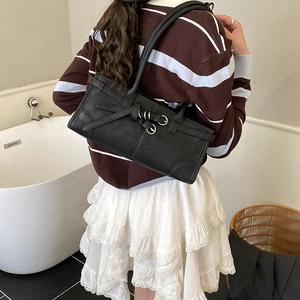 Détail d'un sac baguette rétro noir avec boucles argentées et texture cuir synthétique fine