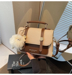 Close-up of a vintage canvas and brown leather crossbody bag with a plush lamb charm