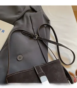 Détail du sac seau marron foncé avec surpiqûres blanches et bandoulière à boucle argentée réglable