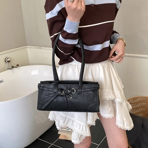 Détail d'un sac porté épaule vintage noir avec boucle métallique et doubles lanières