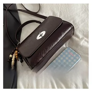 Detail of dark brown vintage leather crossbody bag with silver twist lock and wooden beads