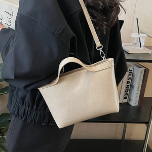 Detailed side view of the beige minimalist leather tote bag worn by a model