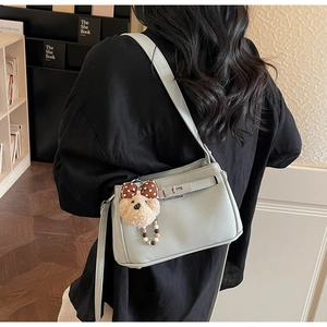Detail of light blue lychee pattern leather bag with silver metal twist lock and bear charm