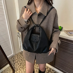 Detail of a vintage black soft leather backpack with snap closure shown in a lifestyle setting