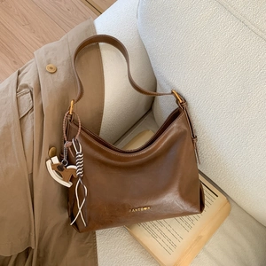 Close-up of brown PU leather bag with gold logo and a wooden rocking horse pendant