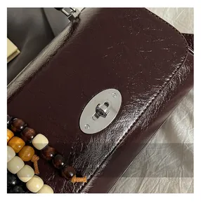 Detailed close-up of dark wine red embossed leather bag with silver metal turn lock closure