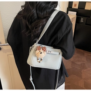 Detail of lychee textured crossbody bag with silver clasp and cute teddy bear charm