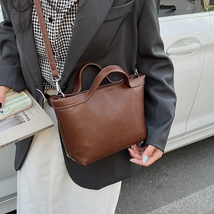 Detail of vintage brown leather tote bag with round handles and adjustable shoulder strap