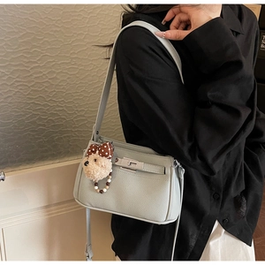 Close-up of light blue shoulder bag with litchi texture and cute bear pendant charm