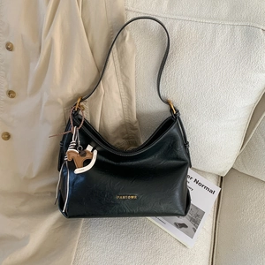 Detail of black Hobo shoulder bag with golden logo, long strap and wooden horse charm