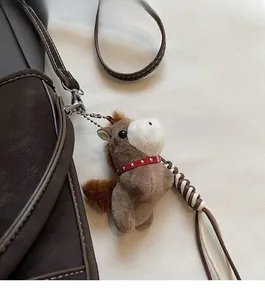 Détail d'un porte-clé poney en peluche marron et blanc sur un sac avec chaîne argentée