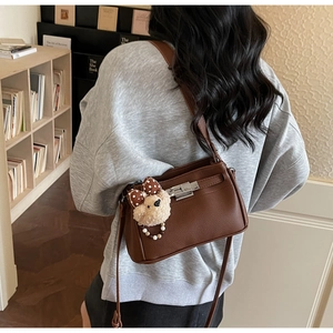 Detail view of brown pebbled leather texture and silver twist lock on the shoulder bag