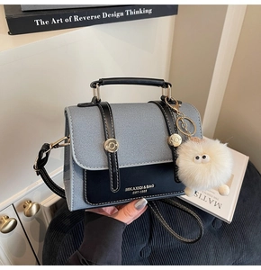 Detail of color-block crossbody bag with metal buckles and white plush monster charm