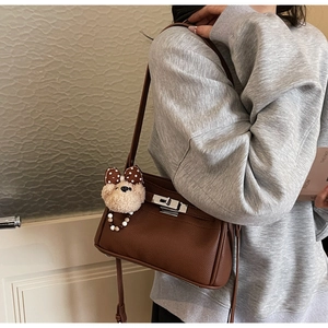 Detail of dark brown leather shoulder bag with silver lock and teddy bear charm