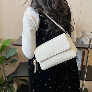 Dettaglio della borsa a tracolla in pelle martellata bianco crema con cinturino decorativo