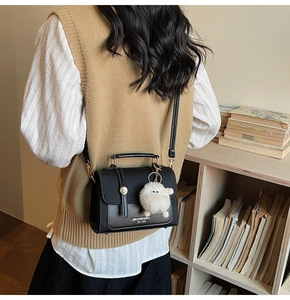 Detail view of black matte leather mini square bag with cute white monster charm on a model