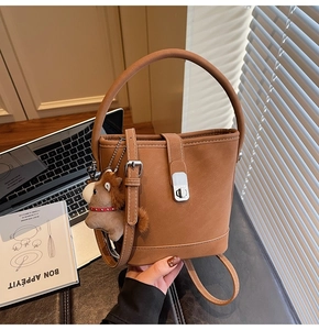 Détail d'un sac seau marron avec fermoir argenté et petit accessoire en peluche poney