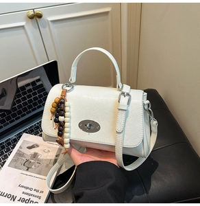 Detail of white wrinkled leather mini bag with silver clasp and wooden bead charm