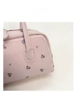 Close-up of pink leather handbag showing delicate floral print and fine stitching detail