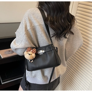 Close-up of black pebble leather handbag with silver twist lock and cute bear charm