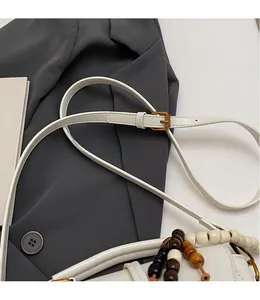 Detail of adjustable white leather shoulder strap with vintage metal buckle and wooden beads