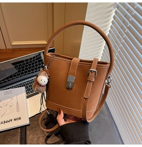 Détail d'un sac seau marron avec finition mate, boucle en métal et charm cheval