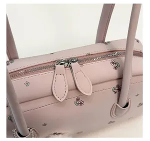 Detail of silver dual zippers and floral leather texture on pink shoulder bag