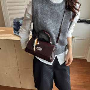 Detailed side view of a vintage dark burgundy crossbody bag with beaded pendant decor