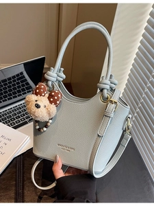 Chic light blue pebble leather bucket bag with cute bear charm and shoulder strap