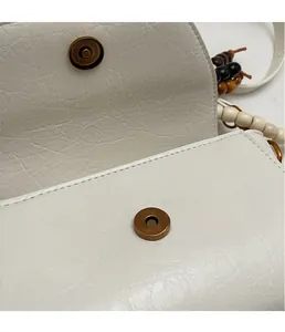Close-up of retro bronze magnetic clasp on cream leather handbag with pebble texture