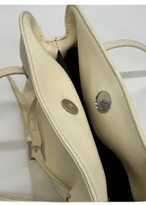 Detailed close-up showing the dual magnetic buckle closure of the cream tote bag