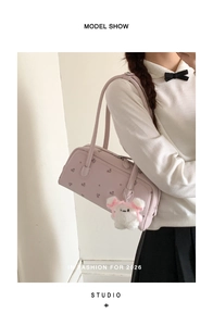 Detail shot of light pink handbag with floral embroidery and cute teddy bear charm