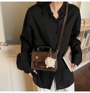 Detail view of brown faux leather mini crossbody bag with cute plush monster charm