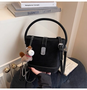 Détail du sac seau noir en daim avec boucle argentée et charm de petit cheval marron
