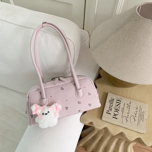 Close-up of a pink floral shoulder bag with a cute white plush bear charm on a white sofa
