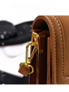 Macro detail of caramel pebble leather bag with golden hardware and white contrast stitching