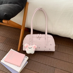 Detail of pink shoulder bag with floral print and white plush puppy pendant