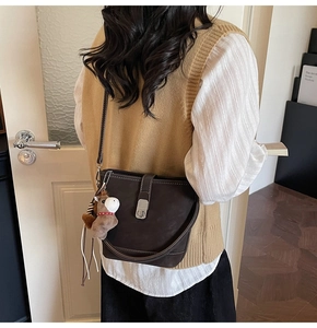Détail d'un sac seau marron foncé avec coutures et charm de sac en forme de petit cheval