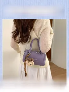 Détail du sac Boston violet avec chaîne argentée et un joli pendentif ours en peluche