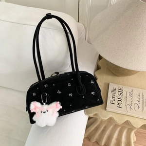 Close-up of black canvas shoulder bag with purple floral embroidery and plush rabbit pendant
