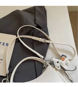 Detalle de correa ajustable y colgante de caballo en un bolso de mano de cuero beige