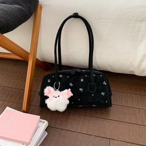 Detail of black suede shoulder bag with purple floral embroidery and puppy charm