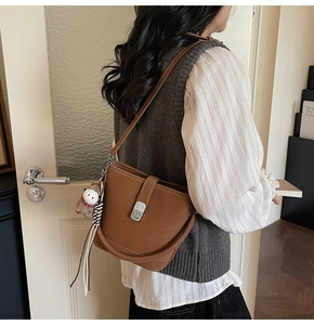 Détail d'un sac seau en cuir marron avec fermoir rotatif argenté et breloque à gland