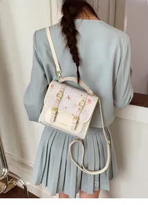 Detail of cute cream PU crossbody bag with cartoon bear prints on blue suit model