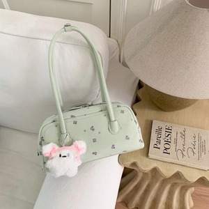 Close-up of mint green floral handbag with cute white plush bunny charm on white sofa