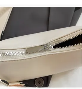 Primer plano de una cremallera metálica plateada en un bolso de cuero blanco crema